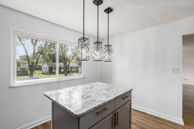 kitchen featuring light stone counters, dark hardwood / wood-style floors, a chandelier, decorative light fixtures, and a kitchen island