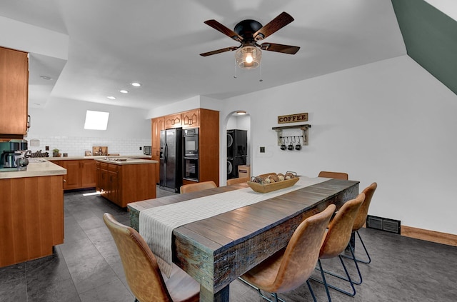 dining space featuring dark tile patterned flooring, ceiling fan, and stacked washer and dryer