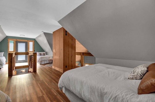 bedroom with lofted ceiling, dark wood-type flooring, and wood walls