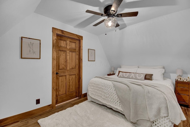 bedroom featuring wood-type flooring, vaulted ceiling, and ceiling fan