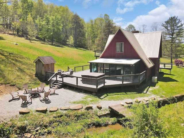 back of house with a sunroom, a yard, a fire pit, and a deck