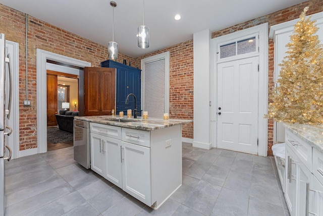 kitchen featuring dishwasher, sink, brick wall, and a center island with sink