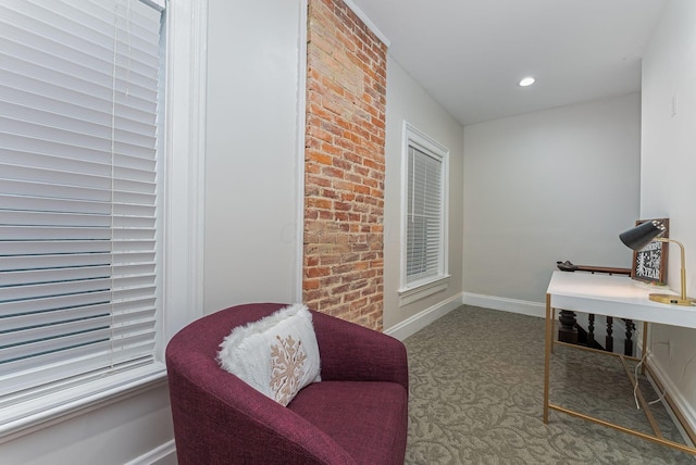 home office with carpet floors and brick wall