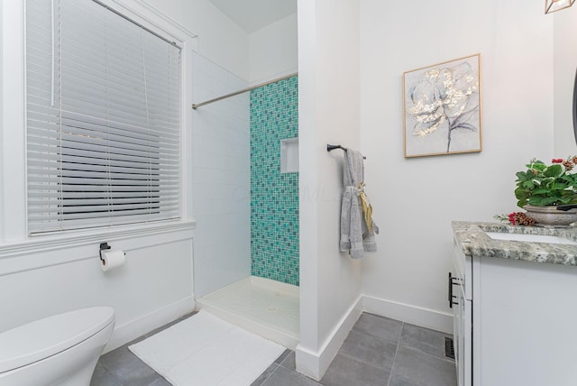 bathroom featuring tile patterned flooring, vanity, tiled shower, and toilet