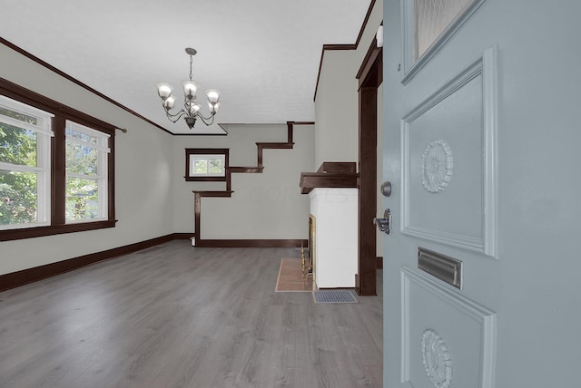 interior space featuring light hardwood / wood-style flooring, ornamental molding, and a notable chandelier