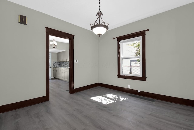 unfurnished room with hardwood / wood-style flooring and a chandelier