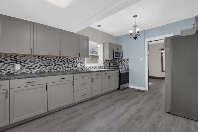 kitchen with sink, hanging light fixtures, stainless steel appliances, gray cabinets, and light wood-type flooring