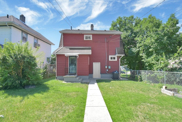 rear view of property with central air condition unit and a yard