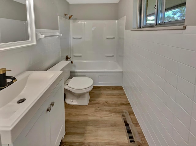 full bathroom with hardwood / wood-style floors, vanity, tile walls, and toilet