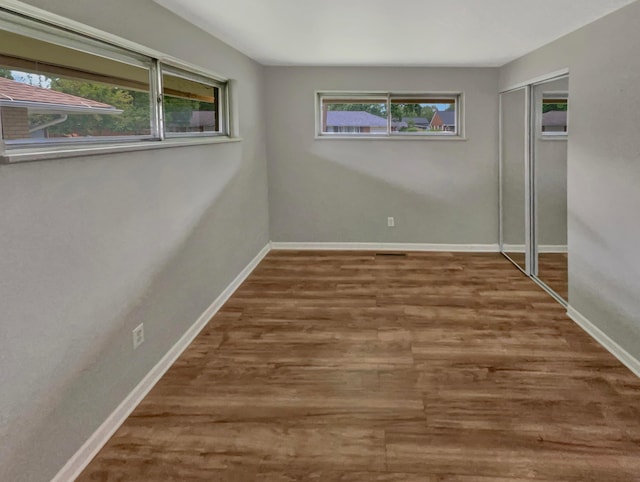 empty room with a healthy amount of sunlight and dark hardwood / wood-style flooring