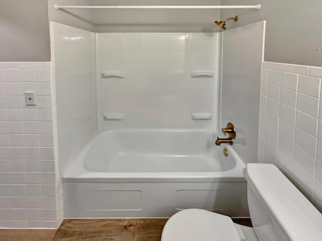 bathroom featuring toilet, tile walls, and bathing tub / shower combination