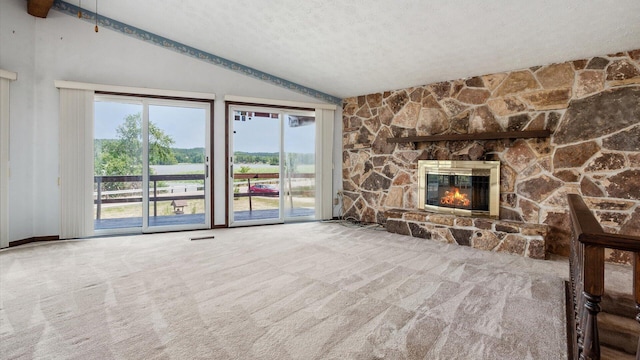 unfurnished living room with vaulted ceiling with beams, a stone fireplace, carpet floors, and a textured ceiling