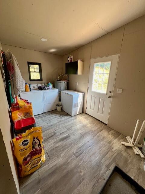 washroom featuring independent washer and dryer, electric water heater, and light hardwood / wood-style flooring