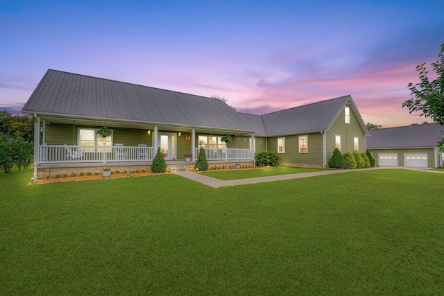 view of front facade featuring covered porch, a garage, an outdoor structure, and a lawn