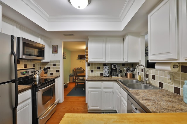 kitchen featuring sink, light wood-type flooring, ornamental molding, white cabinetry, and stainless steel appliances