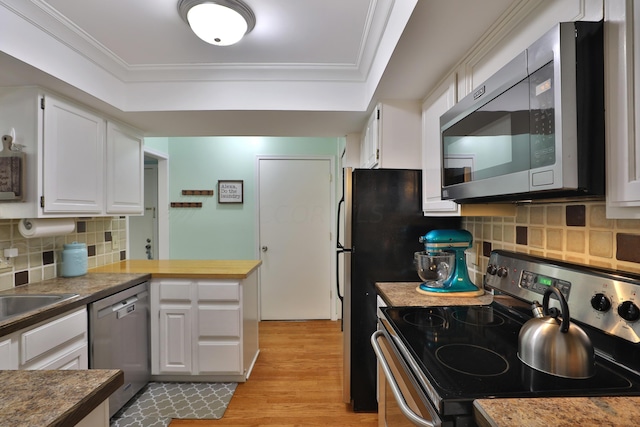 kitchen featuring backsplash, white cabinets, crown molding, light wood-type flooring, and stainless steel appliances