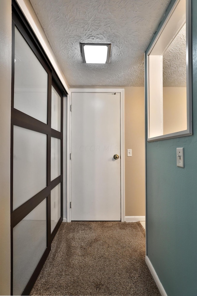 hall featuring carpet and a textured ceiling