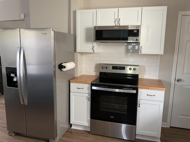 kitchen featuring white cabinetry, stainless steel appliances, and butcher block countertops