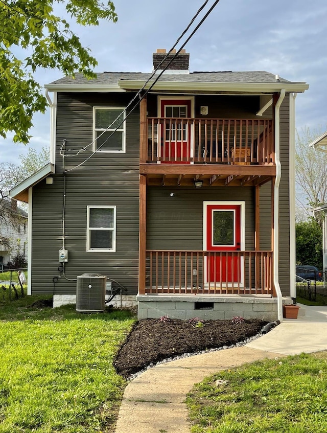 rear view of house featuring cooling unit, a balcony, and a lawn