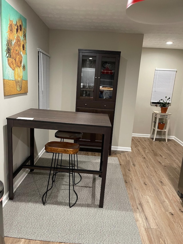 home office with a textured ceiling and light hardwood / wood-style floors