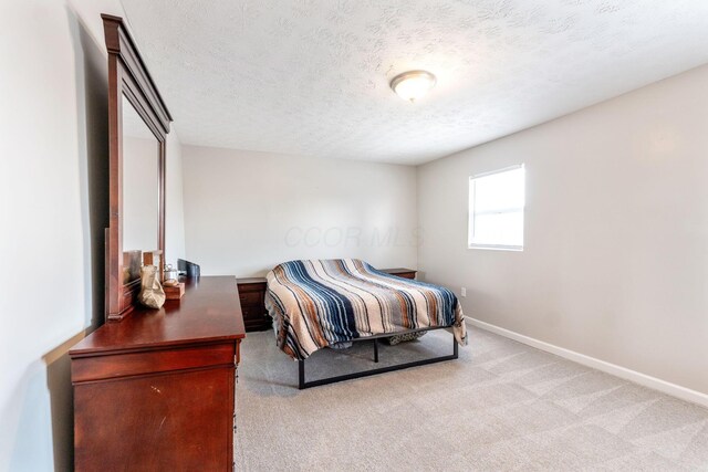 bedroom featuring light carpet and a textured ceiling