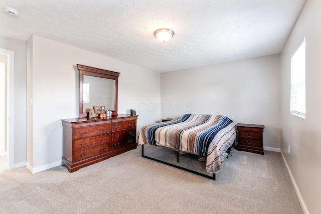 bedroom featuring light colored carpet and a textured ceiling