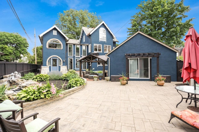 rear view of property featuring a gazebo and a patio