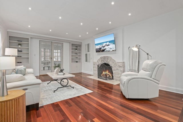 living room with ornamental molding, built in features, dark hardwood / wood-style floors, and french doors