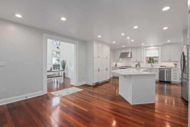 kitchen featuring white cabinetry, backsplash, a center island, stainless steel appliances, and dark wood-type flooring