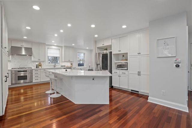 kitchen with appliances with stainless steel finishes, a center island, white cabinets, and dark hardwood / wood-style flooring