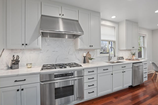 kitchen with light stone counters, appliances with stainless steel finishes, sink, and white cabinets