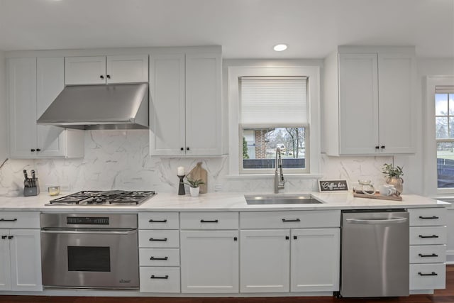 kitchen with white cabinetry, sink, light stone counters, and stainless steel appliances