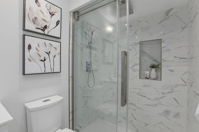 bathroom featuring a shower with shower door and toilet