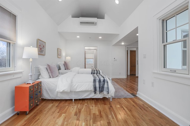 bedroom with wood-type flooring, an AC wall unit, and lofted ceiling