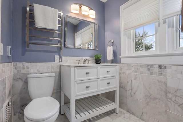 bathroom featuring vanity, toilet, and tile walls