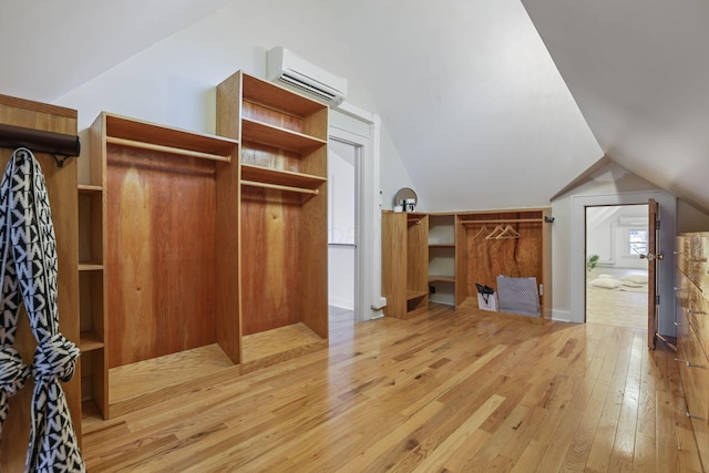 additional living space featuring lofted ceiling, a wall mounted AC, and light wood-type flooring