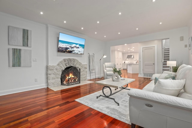 living room featuring crown molding, a fireplace, and hardwood / wood-style floors