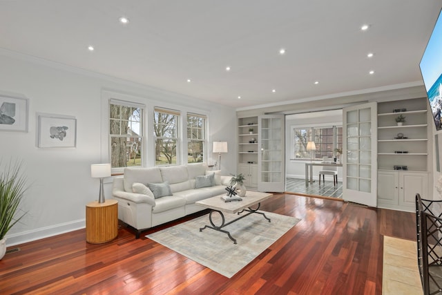 living room with french doors, ornamental molding, hardwood / wood-style floors, and built in features