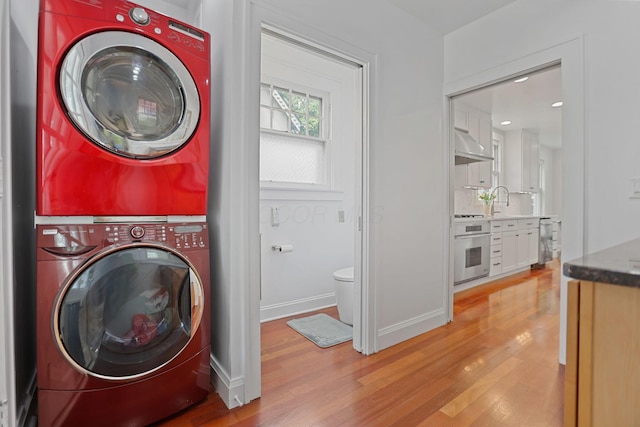 washroom with stacked washer / dryer, sink, and light hardwood / wood-style floors