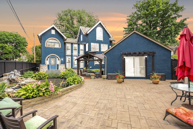 back house at dusk with a gazebo and a patio area