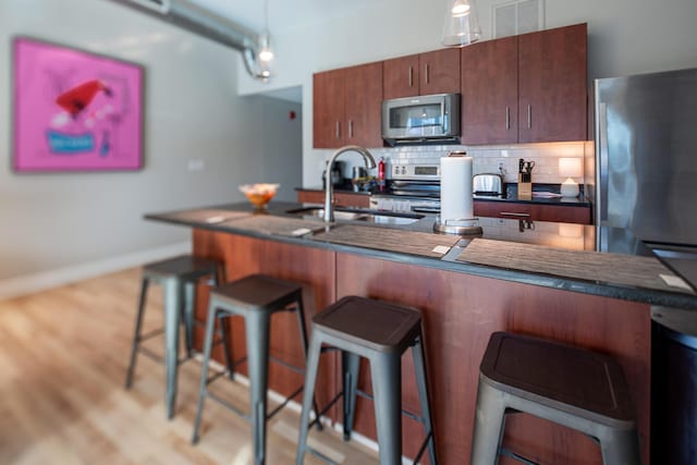 kitchen with sink, backsplash, a breakfast bar area, and appliances with stainless steel finishes