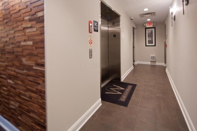 hallway with dark tile patterned floors and elevator