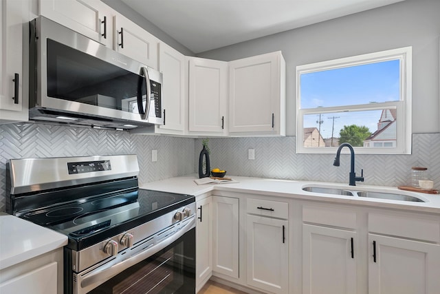 kitchen featuring white cabinets, appliances with stainless steel finishes, backsplash, and sink