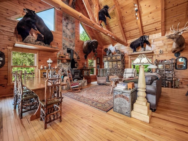 interior space featuring wood walls, wooden ceiling, a wood stove, light wood-type flooring, and beam ceiling