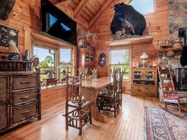 dining space with light hardwood / wood-style floors, a wealth of natural light, wooden walls, and wood ceiling