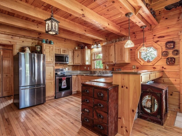 kitchen with light hardwood / wood-style floors, wooden walls, hanging light fixtures, and appliances with stainless steel finishes