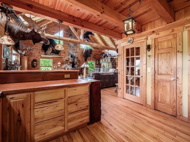 kitchen with wooden ceiling, hanging light fixtures, wooden walls, beamed ceiling, and light hardwood / wood-style floors