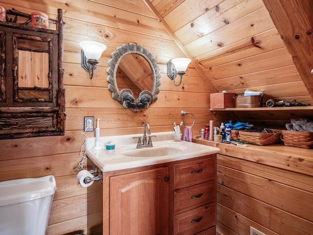 bathroom featuring toilet, vanity, vaulted ceiling, and wooden walls