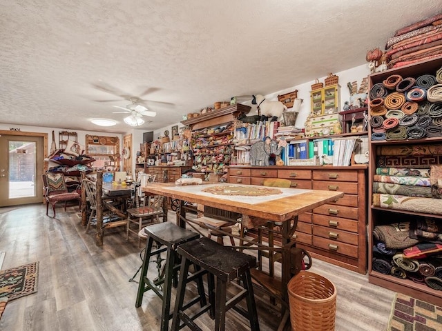 dining room with hardwood / wood-style flooring, ceiling fan, and a textured ceiling