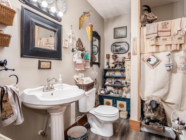 bathroom featuring wood-type flooring, a textured ceiling, toilet, and sink